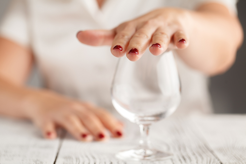 Detail of a lady's hand over an empty wine glass