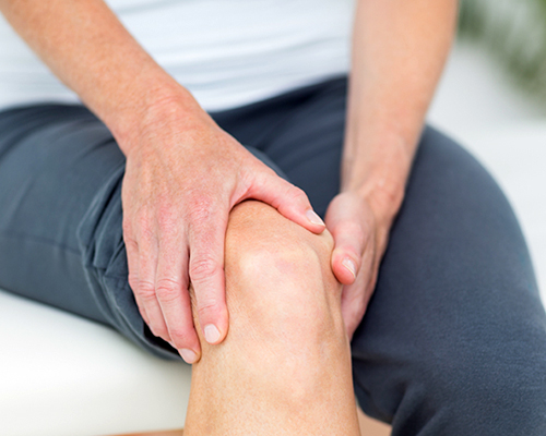 Woman sitting in medical area, holding knee