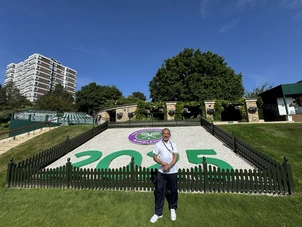 Podiatrist Saj at Wimbledon, standing in front of the 2025 Welcome Sign! 