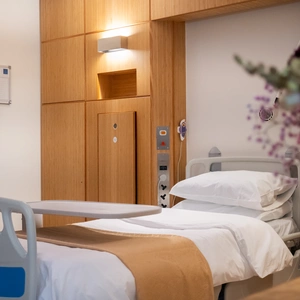 An image of the Superior Room at The London Clinic, with a focus on the patient bed but with flowers in the foreground 